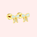 Blue and gold bow earring on a light pink background.