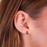 A close up shot of a girl wearing the Christmas tree flat back earrings in gold.