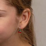 Close-up of a girl wearing a silver cherry hoop earring with a neutral background