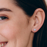Close-up of a woman's ear wearing a diamond stud earring.
