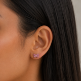 A close-up of a girl's ear wearing a small butterfly-shaped stud earring with pink rhinestones.