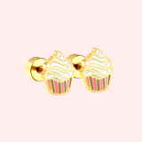 Gold cupcake-shaped earrings on a pink background