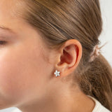 Close-up of a girl wearing a floral earring with a blurred background