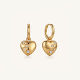 A pair of gold heart-shaped hoop earrings with small clear gemstones, shown on a clean off-white background.