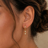 Close-up of model wearing Gold Double Bezel Drop Earrings with two bezel-set clear cubic zirconia stones
