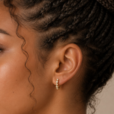 Close-up of model wearing Gold Mini Bezel Heart Huggie Earrings with clear cubic zirconia stones set in delicate heart-shaped bezels