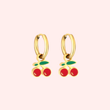 Gold cherry hoop earrings on a light pink background