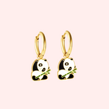 Gold panda hoop earrings on a pink background.