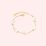 Gold bracelet with butterfly-shaped charms on a light pink background