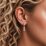 Close-up of model wearing Silver Double Pear Pavé Hoop Earrings with two pear-cut cubic zirconia drops and a crystal pavé huggie hoop