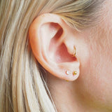 Close-up of a girl with gold hoop and stud earrings.
