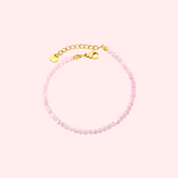 Pink beaded bracelet with a gold clasp on a light pink background