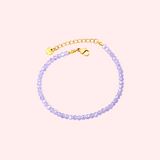 Lavender beaded bracelet with gold clasp on a light pink background