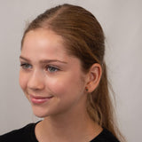 Girl wearing gold rocket earrings against a plain background