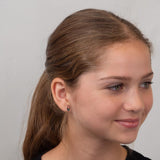 Girl wearing silver rocket earrings against a plain background.