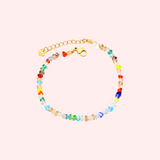 Colorful beaded bracelet with a gold clasp on a light pink background