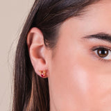Close-up of a girl wearing a gold Christmas earring with a neutral background.