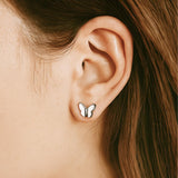 Silver Butterfly-shaped earring worn on a girl's ear.