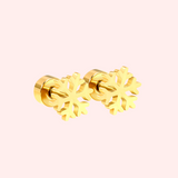 Gold snowflake-shaped earrings on a light pink background