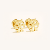 Gold snowflake-shaped earrings on a light pink background