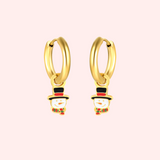 Gold hoop earrings with snowman charms on a light pink background.