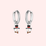 Silver hoop earrings with snowman charms on a light pink background.
