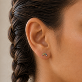 A girl wearing a pair of silver rainbow earrings with multi-coloured gems.