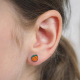Close-up of a girl wearing a small peach-shaped earring.