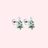 Pair of silver Christmas tree-shaped earrings on a light pink background