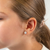 Close-up of an ear wearing a floral earring with blurred background