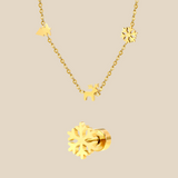 A gold Christmas charm necklace and a snowflake earring on a beige background.
