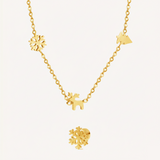 A gold Christmas charm necklace and a snowflake earring on a beige background.