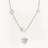 A silver Christmas charm necklace and a snowflake earring on a beige background.