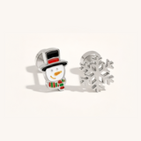 A silver Christmas set with snowflake and snowman earrings on a beige background.