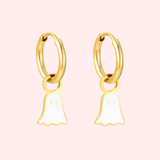 Gold hoop earrings with ghost charms on a pink background