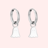 Silver hoop earrings with ghost charms on a pink background