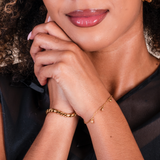 Close-up of a woman's hand wearing gold bracelets with a blurred background.