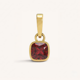 Gold pendant with a garnet gemstone on a white background.