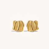 Gold earrings with wavy design on a light beige background