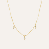 Gold necklace with small diamond pendants on a light beige background