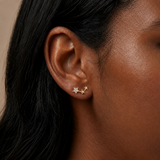 Close-up of model wearing Gold Celestial Trio Flat Back Earrings with three star-shaped details and clear cubic zirconia stones
