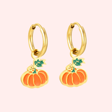 Gold hoop earrings with pumpkin charms on a light pink background