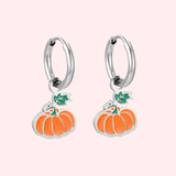 Silver hoop earrings with pumpkin charms on a light pink background