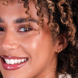 Closeup of a woman wearing rope trim gold earrings.