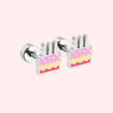 Pair of earrings shaped like birthday cakes with pink and yellow layers on a pink background.