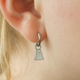 Silver hoop earring with a ghost charm worn by a girl.