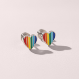 Heart-shaped rainbow earrings on a light pink background