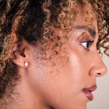 Close-up of a woman's face with curly hair and a diamond earring.