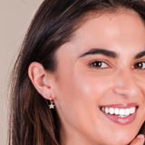 Close-up of a woman wearing gold star-shaped earrings with a neutral background