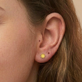 A girl wearing a pair of yellow and orange sunshine flat back earrings.